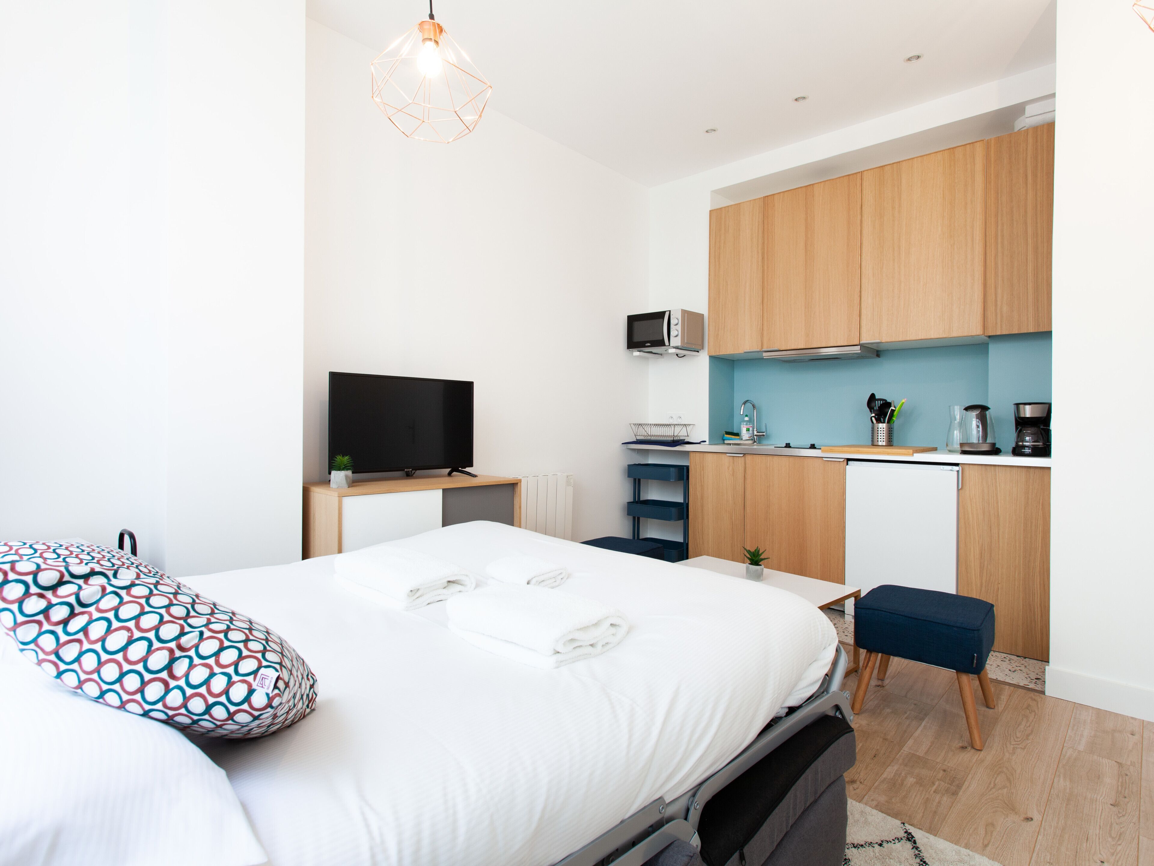 Une chambre moderne équipée d’un lit, d’une télévision et d’une kitchenette.