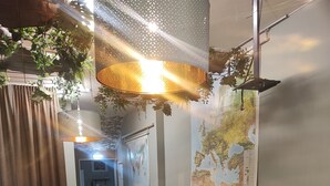 A modern lounge area with green upholstered chairs, a round table, and a map on the wall. - Sjugare Bed & Breakfast (Leksand)