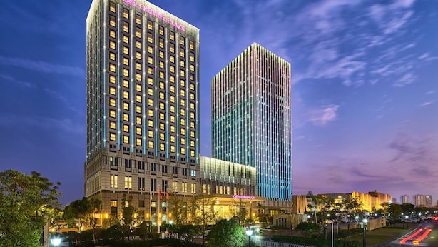 A high-rise hotel with illuminated windows and a prominent sign. - Crowne Plaza Wuhan Development Zone by IHG (Wuhan)