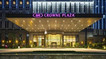 L’entrée d’un hôtel se distingue par sa façade en verre, un espace d’entrée abrité et une enseigne indiquant « CROWNE PLAZA ».