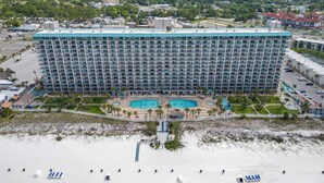 Ein großes Hotel mit mehreren Etagen, einem Poolbereich und einem Strand im Vordergrund.