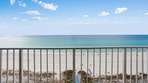 Blick auf einen Strand vom Balkon mit Geländer, feinem Sand und dem Meer.
