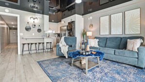 Ein modernes Wohnzimmer mit einem blauen Sofa, einem Couchtisch und einem gemusterten Teppich.