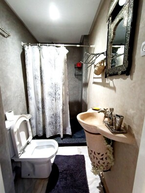 A compact bathroom with a toilet, sink, and shower area.
