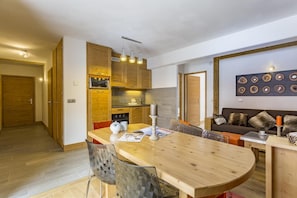 Een moderne keuken met houten kastjes, een eettafel en een inbouwoven.