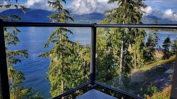 Une pièce dotée d’une grande fenêtre donnant sur un lac, entouré d’arbres et de montagnes.