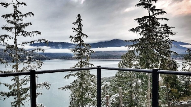 Un balcon avec vue sur un lac et des arbres couverts de neige.