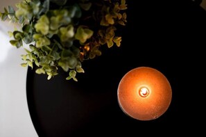A candle in a black holder with a plant beside it. - Fabrì 171 (Pescara)
