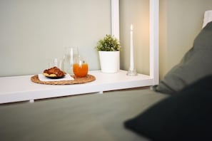 A breakfast setup on a white shelf with a croissant, orange juice, and a candle. - Fabrì 171 (Pescara)