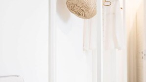 A white wardrobe with shelves and hanging space, a woven basket, and a white chair. - Fabrì 171 (Pescara)