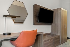A modern room with a wooden desk, a leather chair, a wall-mounted TV, and a large mirror. - Holiday Inn Express & Suites Detroit North - Roseville by IHG (Roseville)