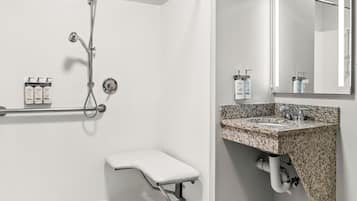 A modern bathroom with a shower, a vanity with a granite countertop, and a large mirror.