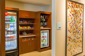 A kitchenette with a refrigerator stocked with beverages, a microwave, and a small freezer. - Holiday Inn Express & Suites Detroit North - Roseville by IHG (Roseville)