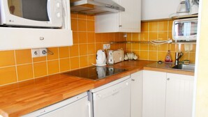 Eine kompakte Küche mit Mikrowelle, Toaster und Kaffeemaschine auf der Arbeitsplatte, einem Geschirrspüler und einem Waschbecken mit Armatur.