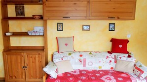 Ein gemütliches Schlafzimmer mit einem hölzernen Bett, einem Schrank aus Holz und einem Regal mit Dekoration.