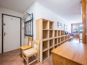 A room with a wooden table, chairs, and a shelving unit against the wall.