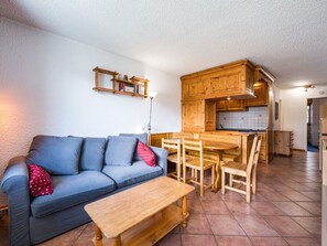 Uma sala de estar com sofá, mesa de centro e um espaço de jantar com cadeiras e mesa de madeira.
