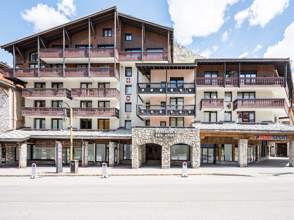 A multi-story hotel with balconies, a stone facade, and signage for ski rental and a restaurant.
