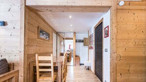 A wooden interior with a dining area, a kitchen in the background, and a wooden door. - Renovated apartment in the heart of Val-d'Isère (Val-d'Isère)