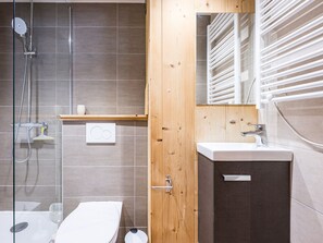A modern bathroom with a shower, toilet, and sink.