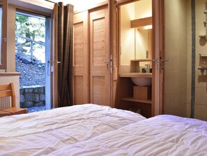 A bedroom with a bed, wooden wardrobe, and a bathroom with a shower and sink. - Charming 3-Star Ski Apartment for 6, 50m from Slopes, Parking, Ski Locker, Méribel (Méribel)
