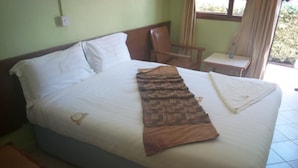 A bed with a patterned blanket, a pillow, and a folded white cloth. - Falls Hippo Point Hotel (Nyahururu)