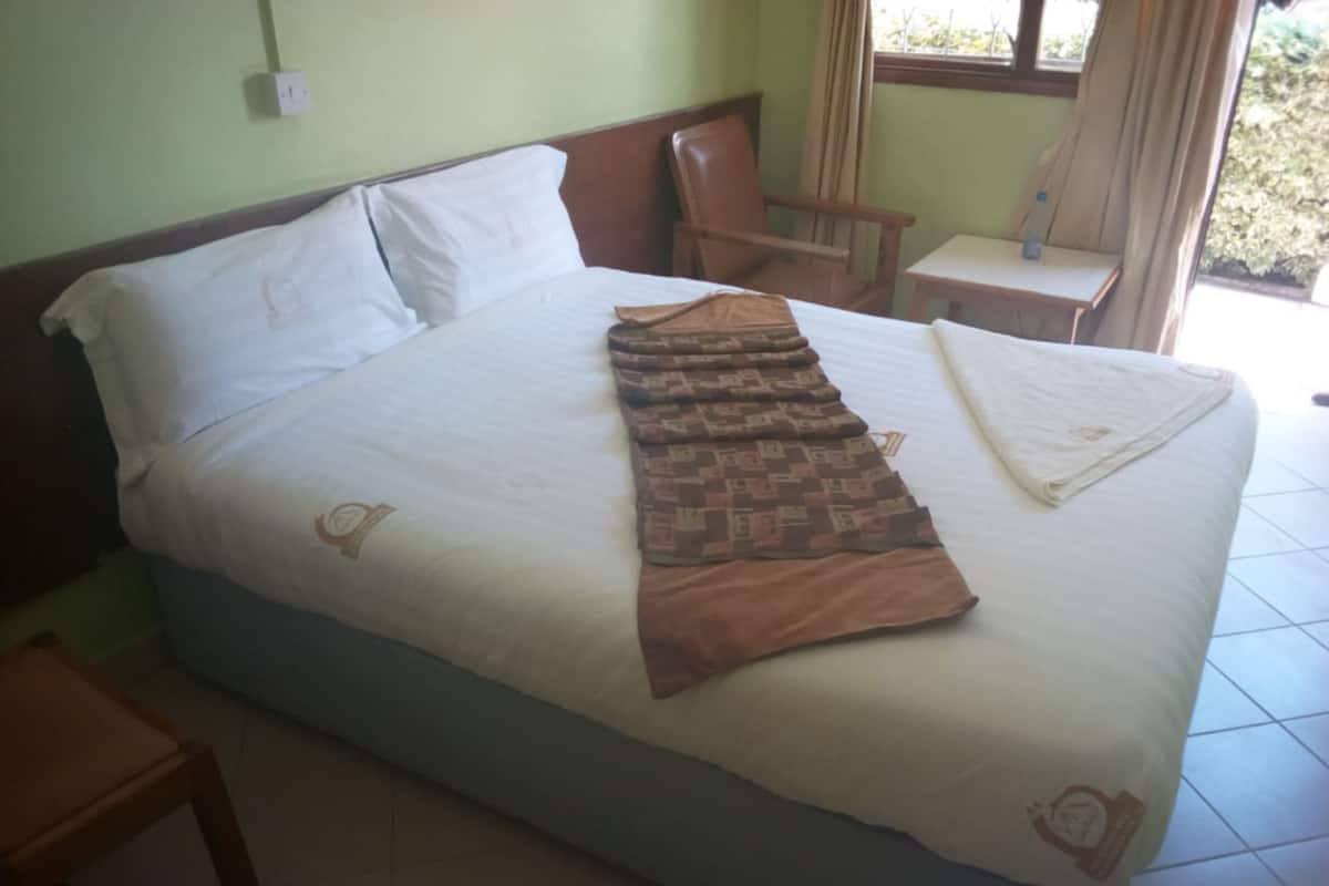 Una cama con un edredón estampado, una almohada y un paño blanco doblado.
