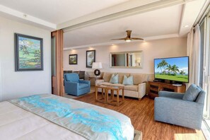 Quarto de hotel com uma cama grande, um sofá, uma televisão e uma mesa de jantar.