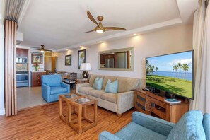 Uma sala de estar moderna com sofá, poltronas, mesa de centro e televisão.