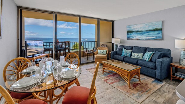 A room with a dining table set for four, a sofa, a coffee table, and a painting on the wall. - Sugar Beach PH31 Front Row Amazing Oceanviews in Highly Upgraded Unit (Kihei)