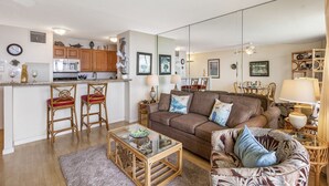 Een ruimtelijk ingerichte leefruimte met een kitchenette, een bank, een salontafel en een eethoek.