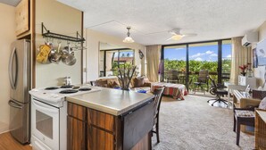 A spacious kitchen with a central island, a dining area with a view, and a balcony with a table and chairs. - Maui Vista 3210 Wonderful unit With New Split AC, Low VO and New Paint and Carpet (Kihei)