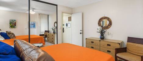 A hotel room with two beds, a dresser, a chair, and a mirror.