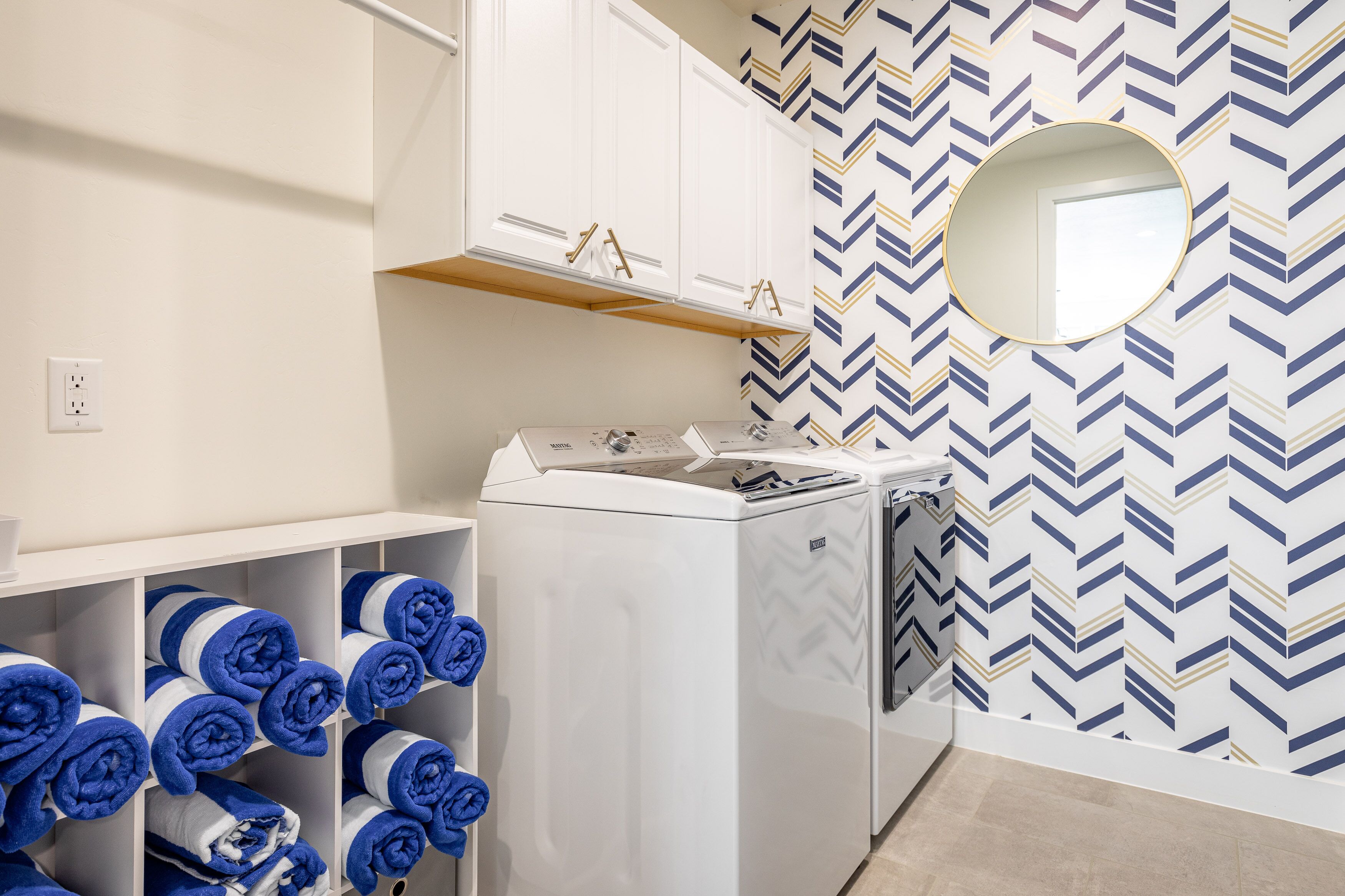 A modern bathroom with a white sink, a mirror, and a towel rack with blue towels.