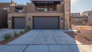 A modern building with two garage doors, a covered outdoor area, and a landscaped driveway.