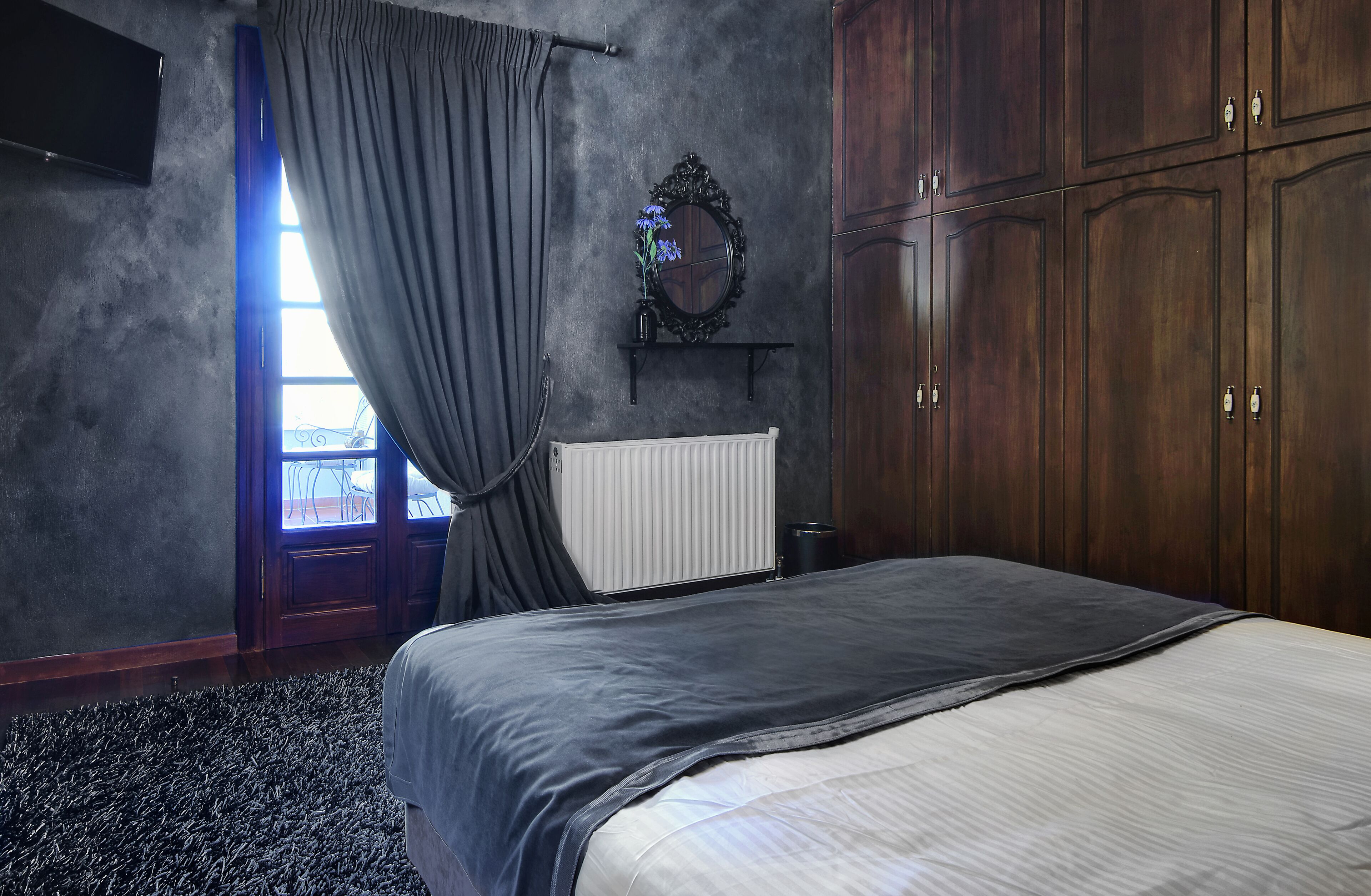 A bedroom with a bed, a dresser, a mirror, and a radiator.