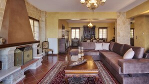 A spacious living room with a fireplace, a large sofa, and a chandelier. - Infinity Villa Ioannina (Ioannina)