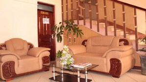 A lobby with two beige sofas, a glass coffee table, and a staircase with wooden railings. - Laikipia Comfort Hotel (Nyahururu)