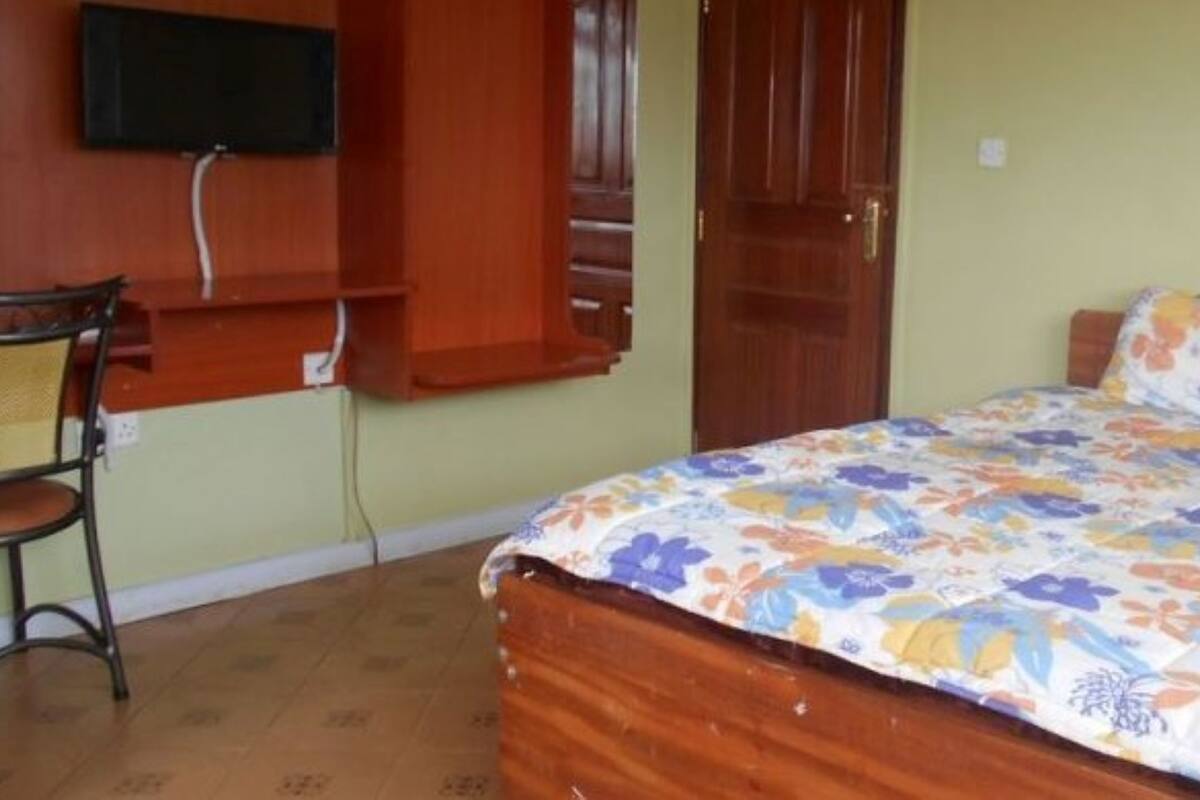 A room with a bed, a chair, a television mounted on the wall, and a door.
