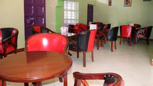 A dining area with wooden tables and chairs, purple doors, and green accents. - Laikipia Comfort Hotel (Nyahururu)