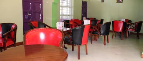 A dining area with wooden tables and chairs, purple doors, and green accents.