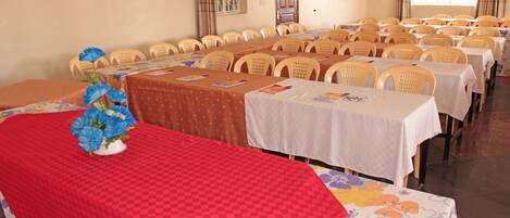 Un salón de conferencias con varias mesas y sillas dispuestas en filas.