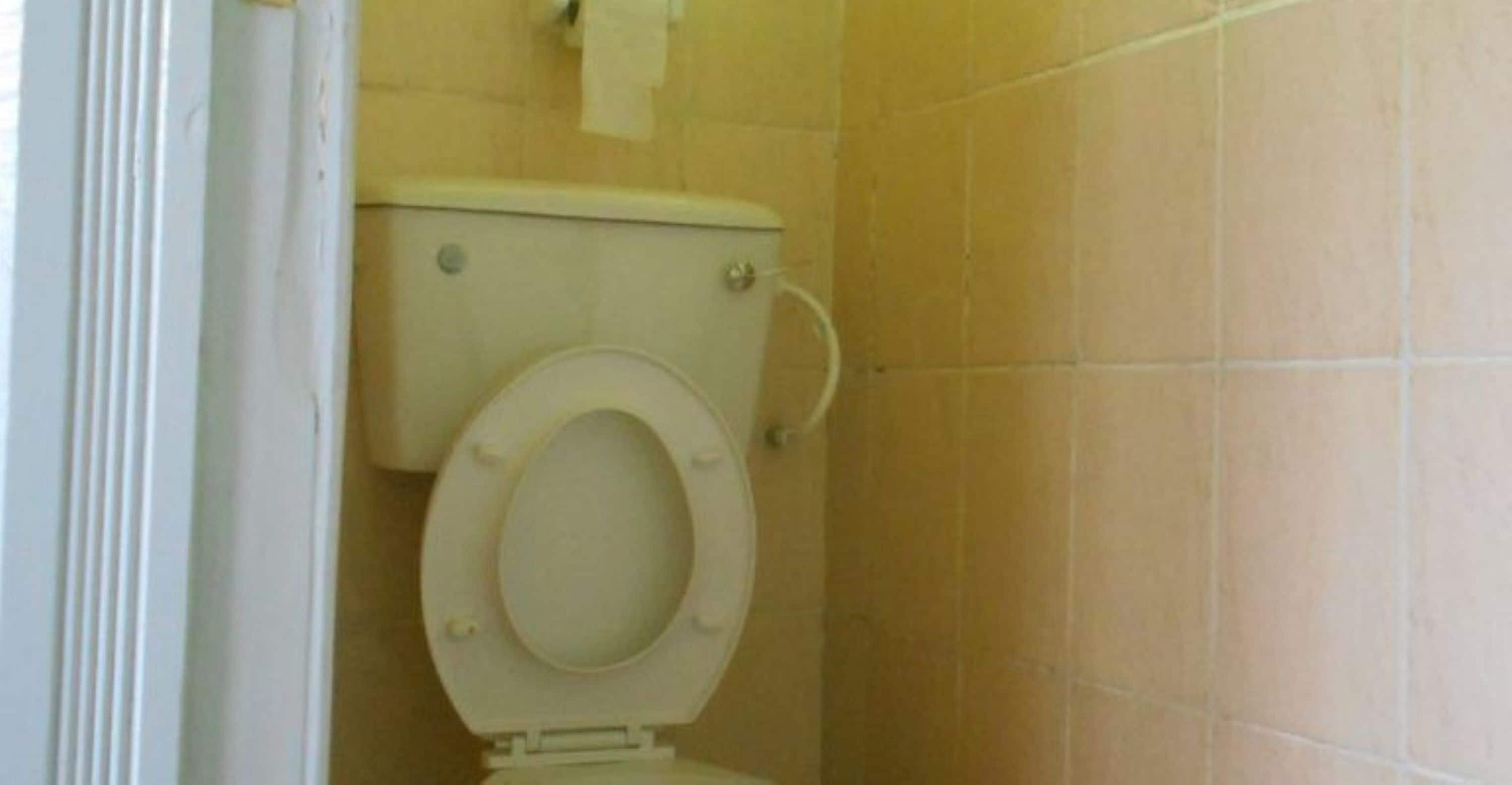 Eine weiße Toilette in einem Badezimmer mit beige gefliesten Wänden.