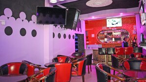 A restaurant interior with red and black chairs, a bar area, and a television mounted on the wall. - Laikipia Comfort Hotel (Nyahururu)