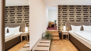 Een moderne hotelkamer met twee bedden, houten vloeren en een wand met een baksteenmotief.