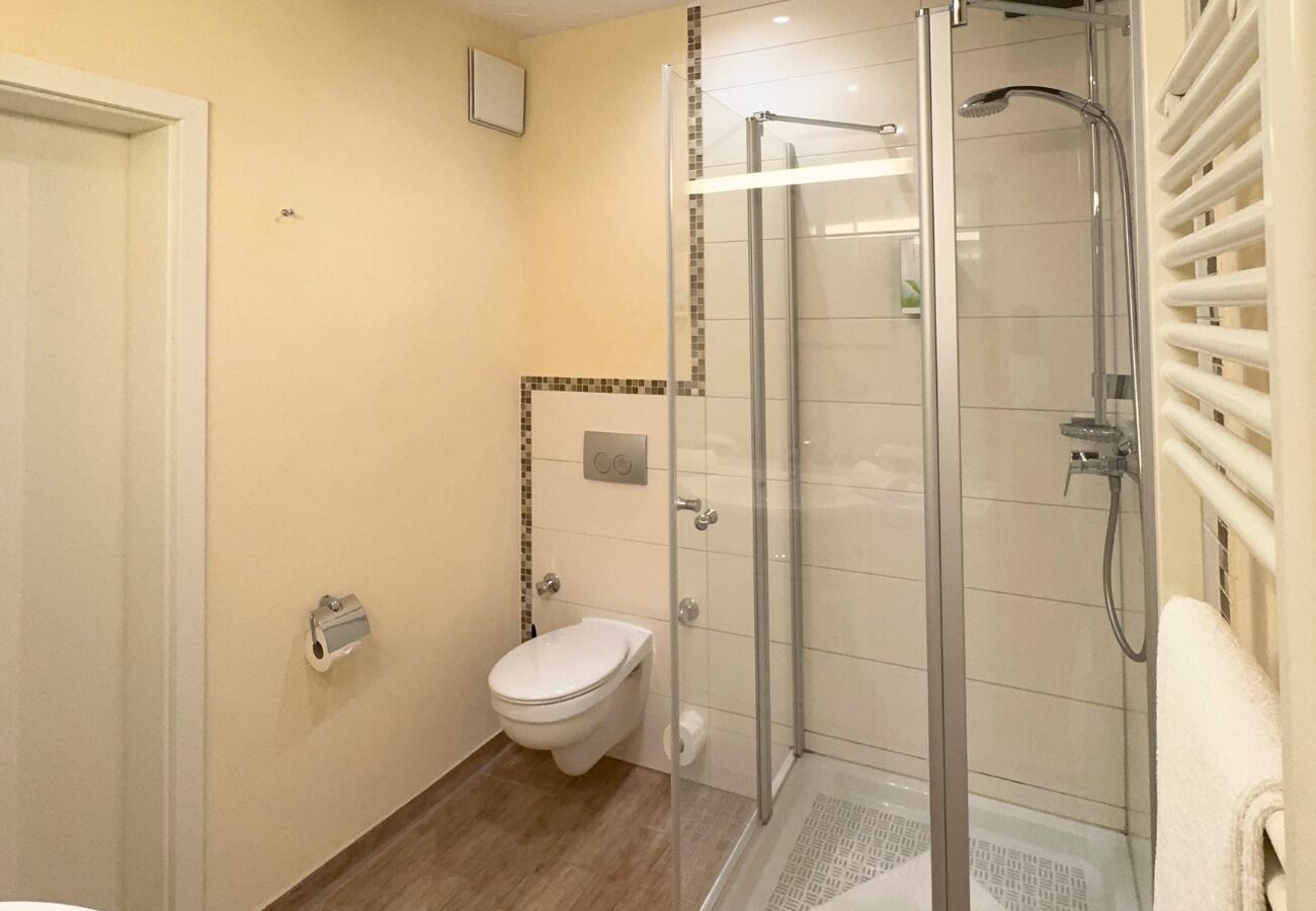 A bathroom with a toilet, a glass-enclosed shower, and a towel rack.