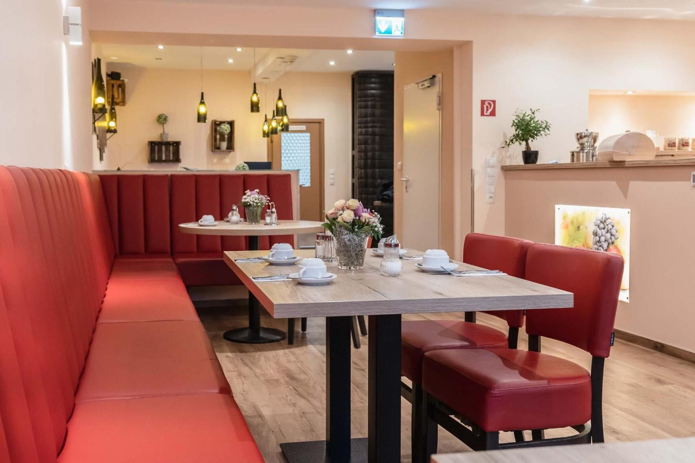 A restaurant with red seating, a wooden table, and a vase of flowers.