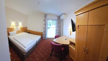 A hotel room with a bed, a desk, a chair, a wardrobe, and a television.
