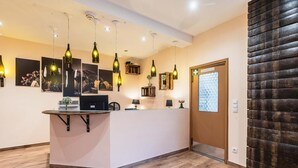 Een receptiegedeelte met een houten receptiebalie, hanglampen, ingelijste kunstwerken en een houten wandpaneel.