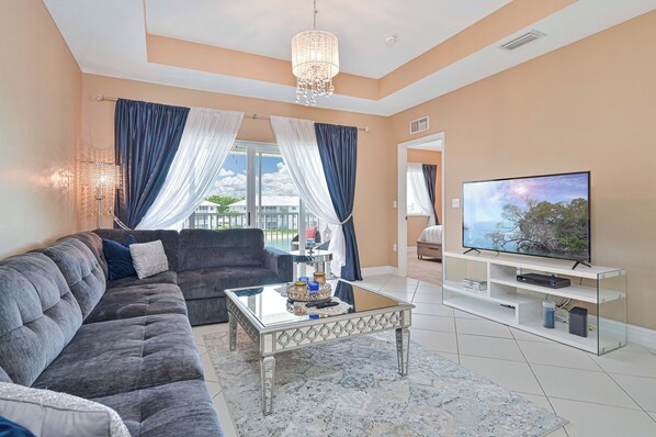 A living room with a sofa, coffee table, TV, and curtains.